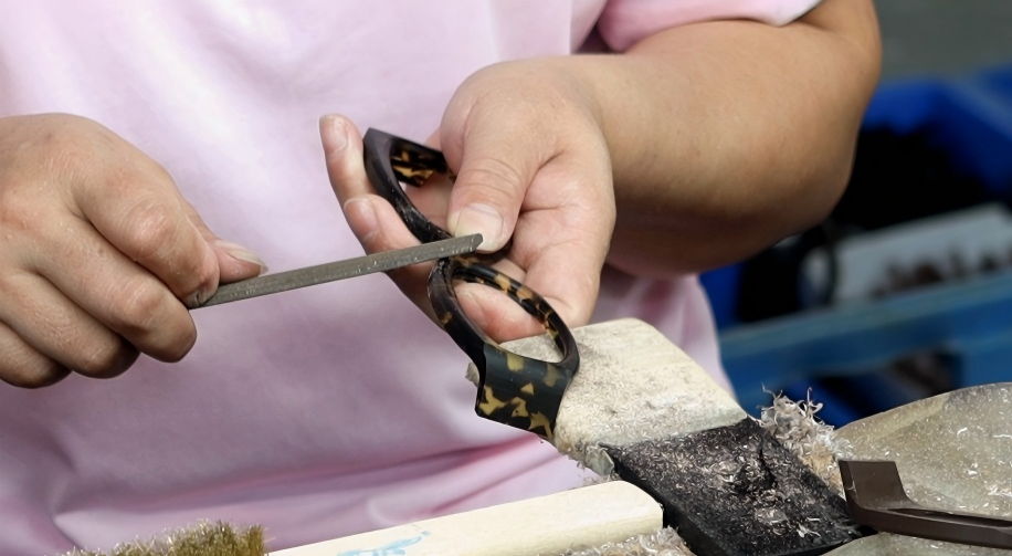 Worker hand polishing acetate eyeglasses frame in eyewear factory workshop