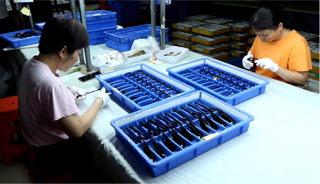 Workers doing final quality inspection for finished acetate eyeglass frames in factory workshop